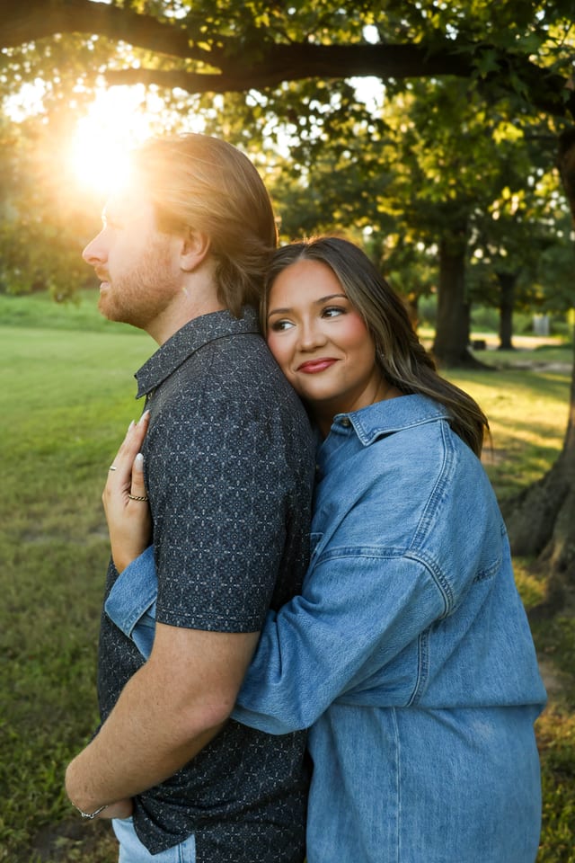 Couple back-to-back at golden hour in a green field